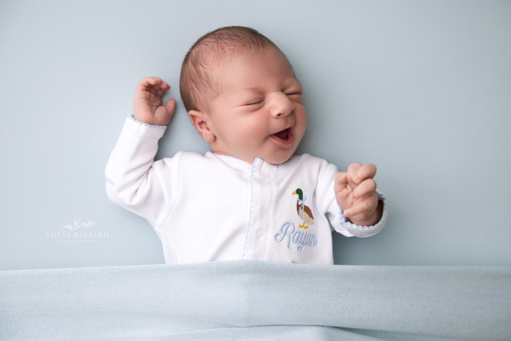 baby boy shares a yawn against a blue backdrop