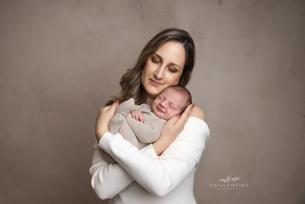 mom shares a soft cuddle with her smiling baby boy