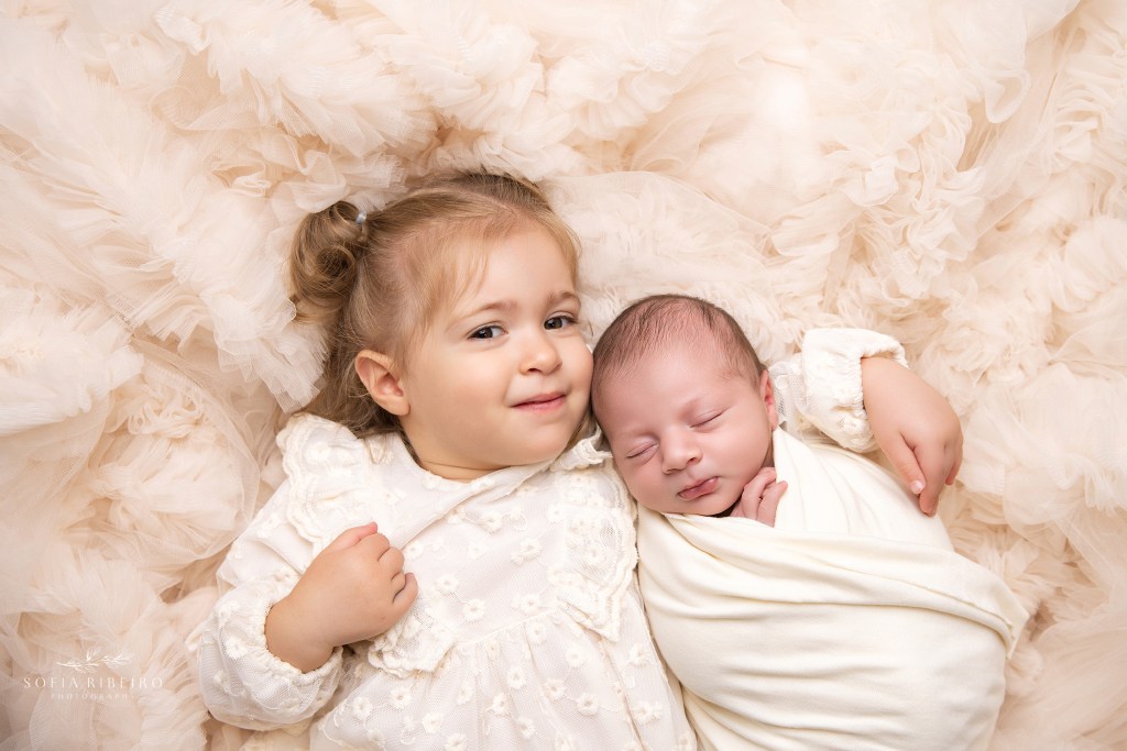 big sister cuddles her newborn baby brother