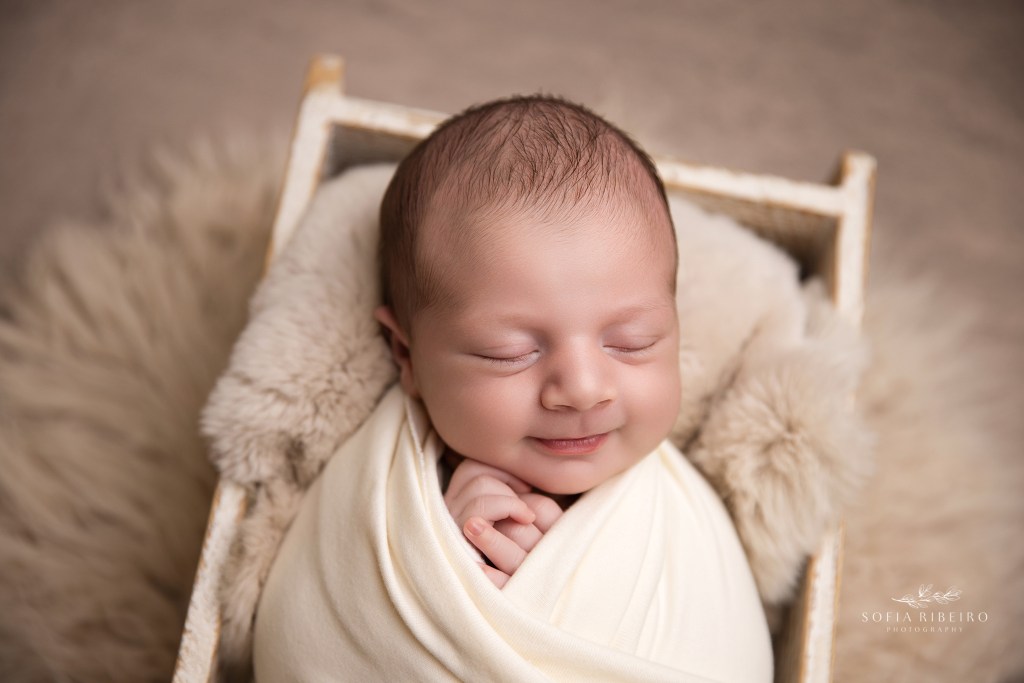 a sweet newborn smile while baby is posed in a prop