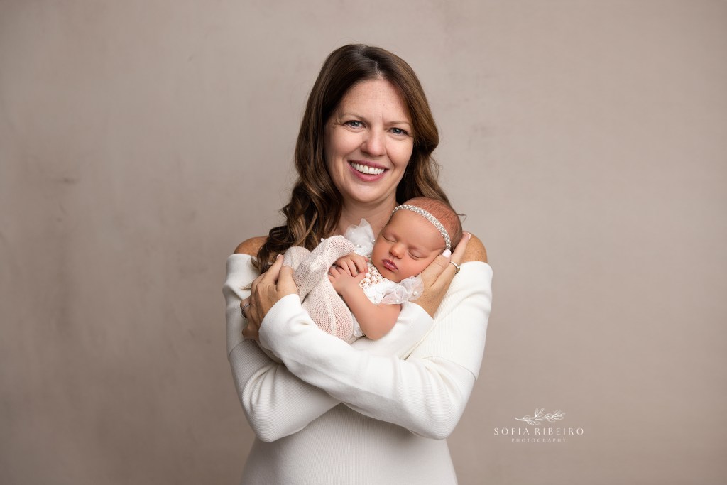 mom snuggles her newest baby girl during a newborn photo session