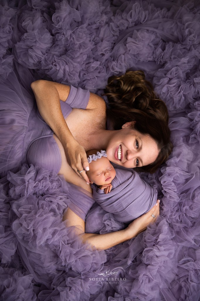 mom and daughter cradled in a bed of purple tulle