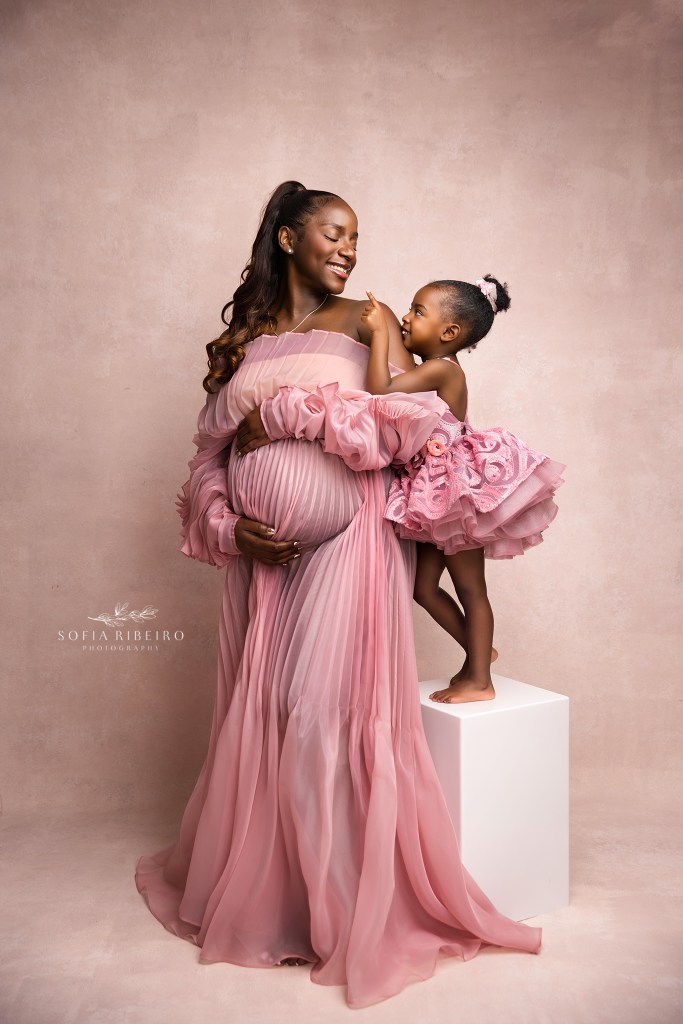 mom and me photo cradling the baby bump in pink with her eldest daughter