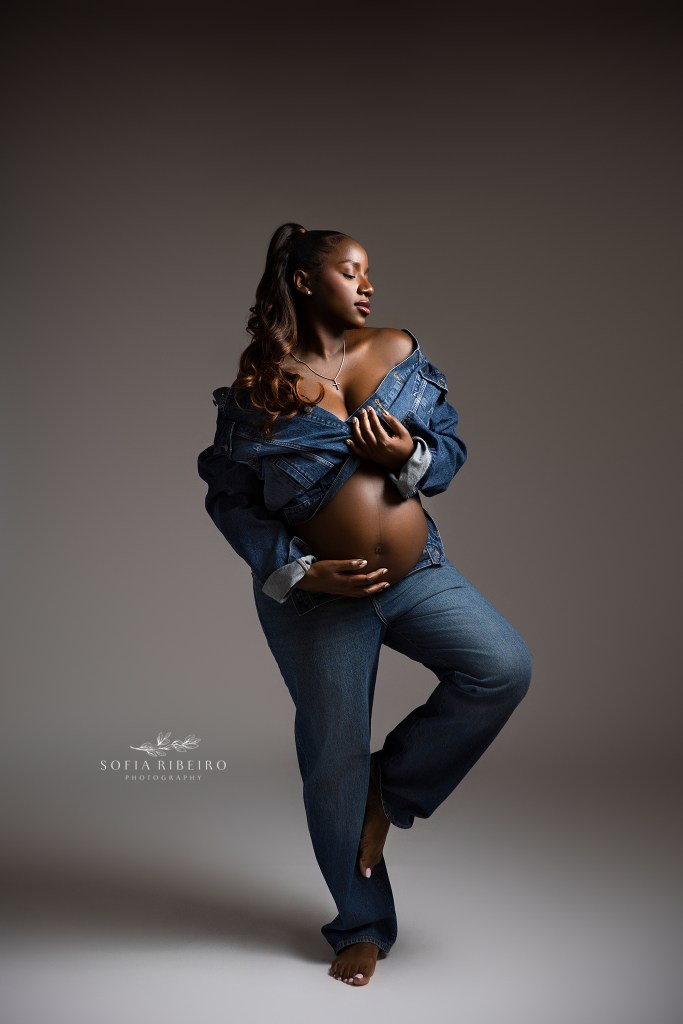 mom sitrkes an pose in matching denim with baby bump exposed